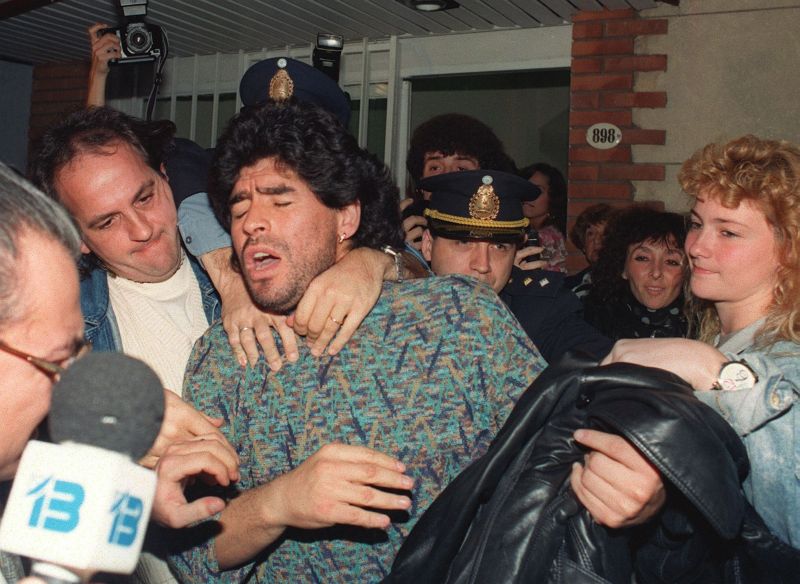(FILES) Argentinian soccer player Diego Maradona (C) is removed by police from a Buenos Aires apartment, 26 April 1991, after being arrested for possession of half-kilo of cocaine. Maradona was suspended by the Italian League 29 March 1991, after an analysis of his urine tested positive for cocaine. (Photo by DANIEL LUNA / AFP) (Photo credit should read DANIEL LUNA/AFP/Getty Images)