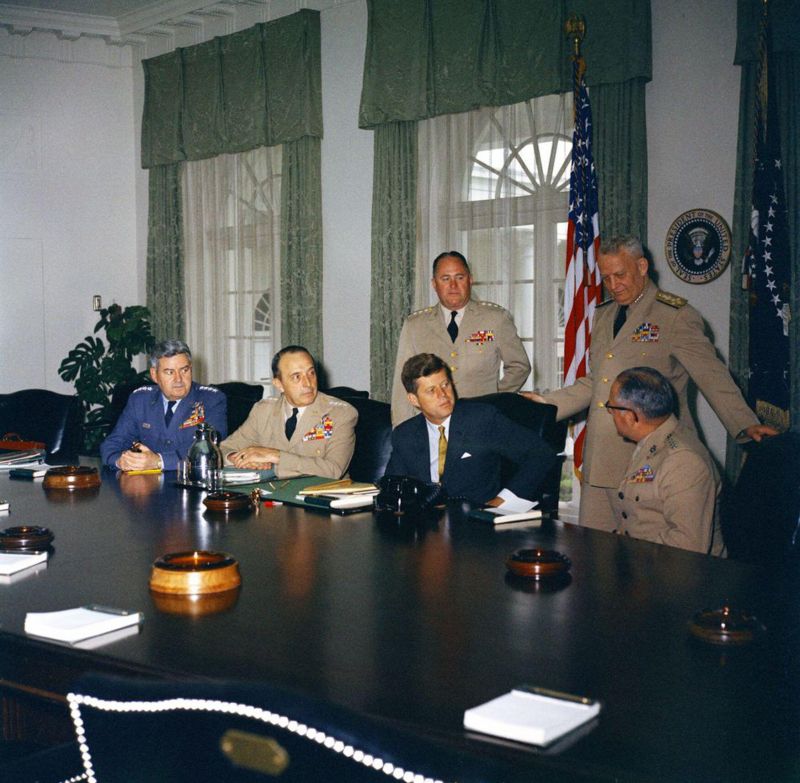 2EBF1WF Meeting with the Joint Chiefs of Staff (JCS), 11:55AM. President John F. Kennedy meets with the Joint Chiefs of Staff. L-R: Vice Chief of Staff of the United States Air Force, General Curtis E. LeMay; Chairman of the Joint Chiefs of Staff, General Lyman L. Lemnitzer; President Kennedy; Chief of Staff of the United States Army, General George H. Decker; Chief of Staff of the United States Navy, Admiral Arleigh A. Burke; Commandant of the United States Marine Corps, General David M. Shoup (seated). Cabinet Room, White House, Washington, D.C.